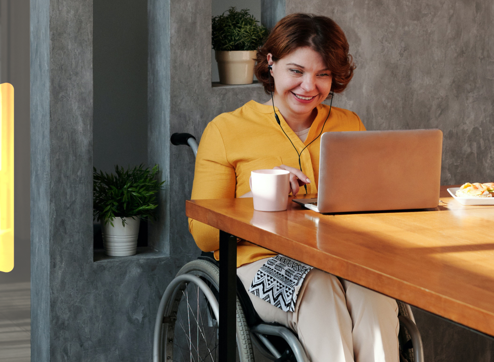 Beispielbild: Barrierefreiheit mit Symbolbild und einer freundlichen Frau im Rollstuhl im Home Office.