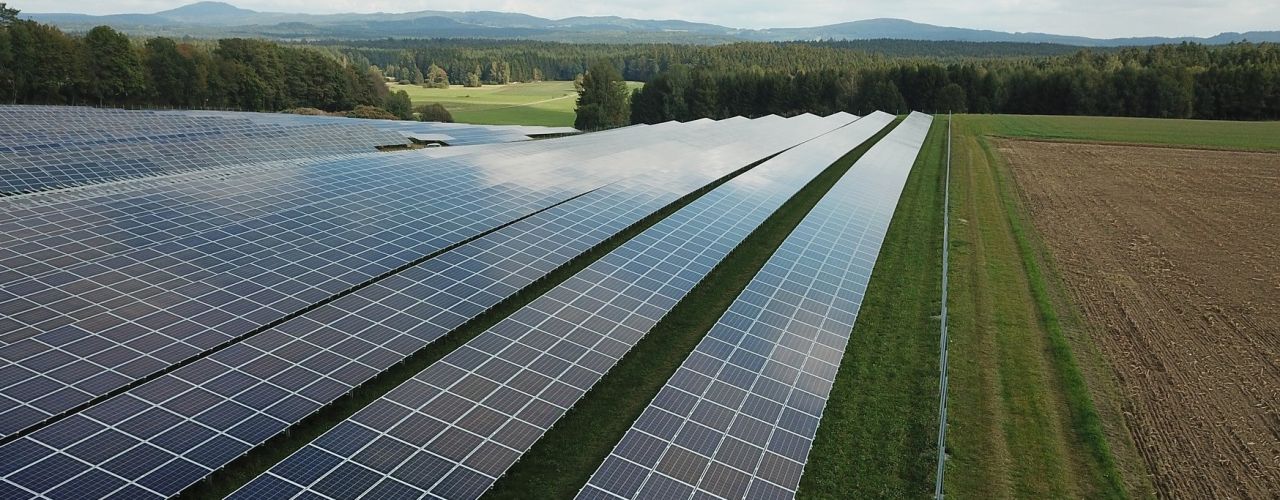 Photovoltaikanlagen inmitten einer grünen Hügellandschaft.