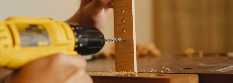 Beispielbild Repariercafe. Ein gelber Bohrer macht Löcher in eine Holzlatte. Beispielbild Repariercafe. Ein gelber Bohrer macht Löcher in eine Holzlatte.