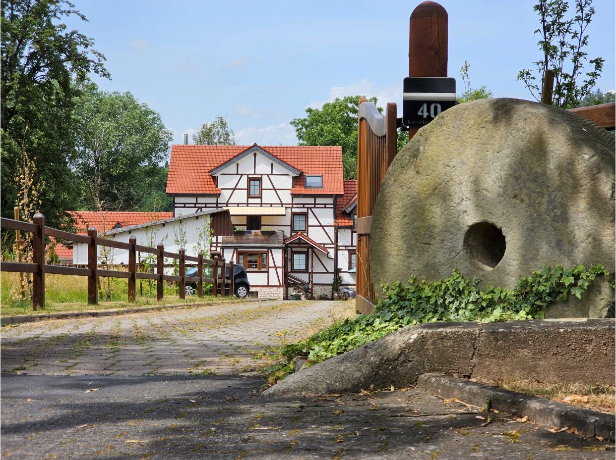 Die Mühle der Familie Paul in heutiger Ansicht 2023. Am Eingang steht ein Mühlstein. @Gemeinde Niestetal