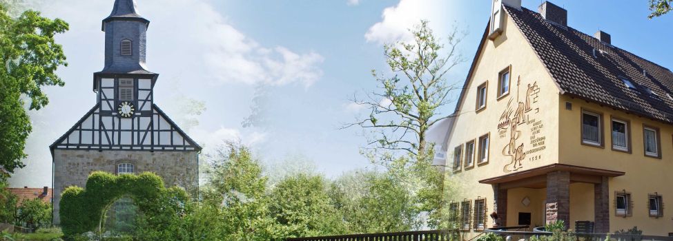 Die Kirche Heiligenrode eingebettet in eine grüne Landschaft, daneben das alte Bürgermeisteramt in Sandershausen.