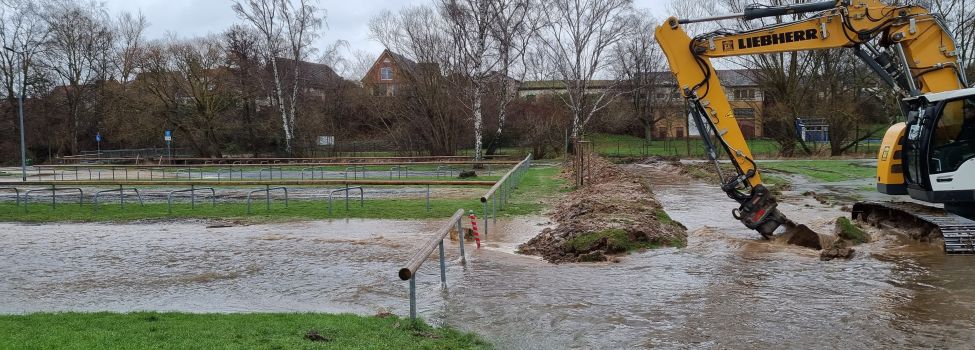 Der von Bürgermeister Brückmann angeordnete, provisorische Graben sorgte bereits beim Bau für einen erhöhten Rücklauf in das Niestebett und verringerte somit drastisch die weitere Überflutung. Zu sehen ist ein Bagger, der einen Graben aushebt.
