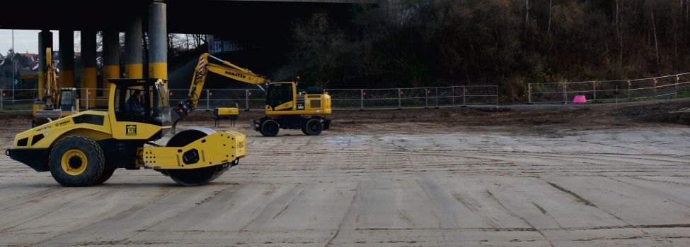 Zu sehen sind zwei Baumaschinen, die zusammen eine Erdfläche planieren