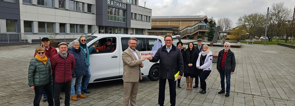 Bürgermeister Brückmann erhält, im Beisein aller ehrenamtlichen Fahrerinnen und Fahrer, den Schlüssel für den neuen E-Bus von Prof. Dr. Hein.