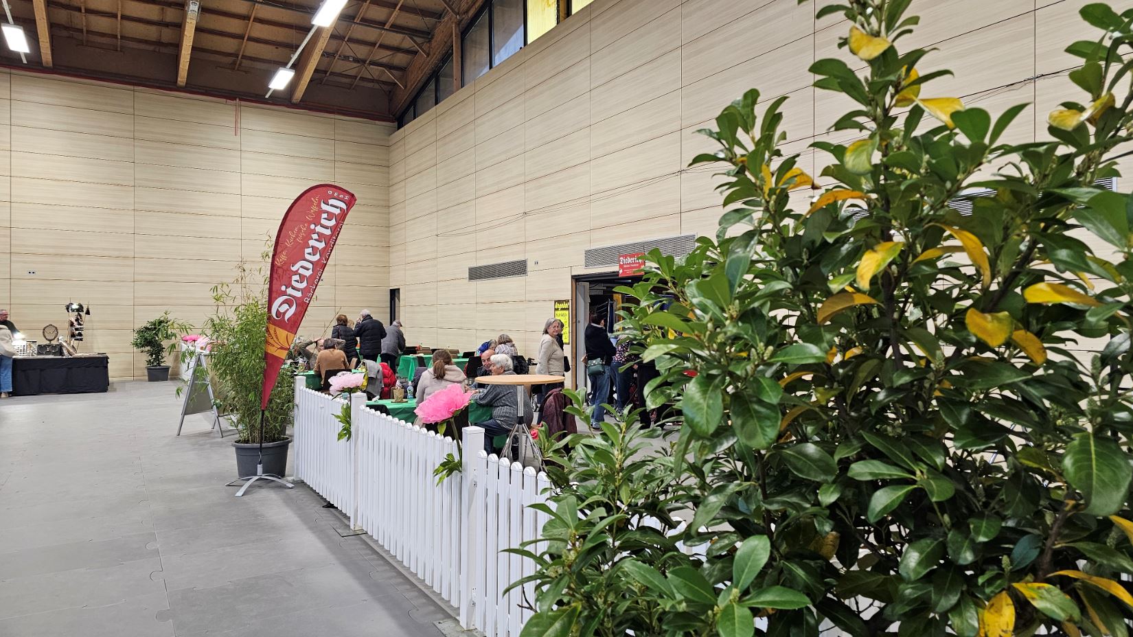 Café Diederich im Innenbereich mit weißem Zaun und grünen Büschen.