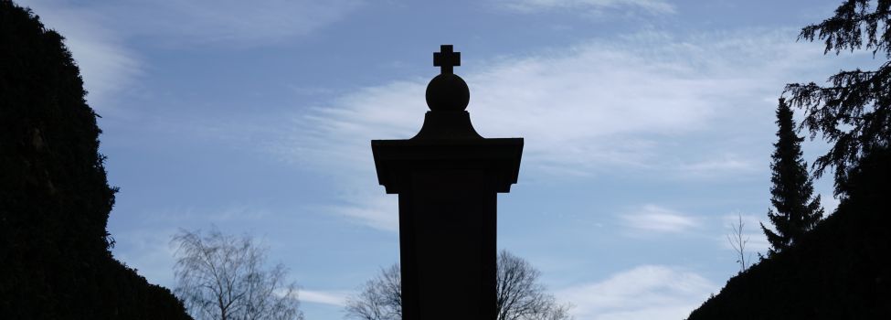 Die Spitze des Gefallenendenkmals mit Kreuz und blauem Himmel