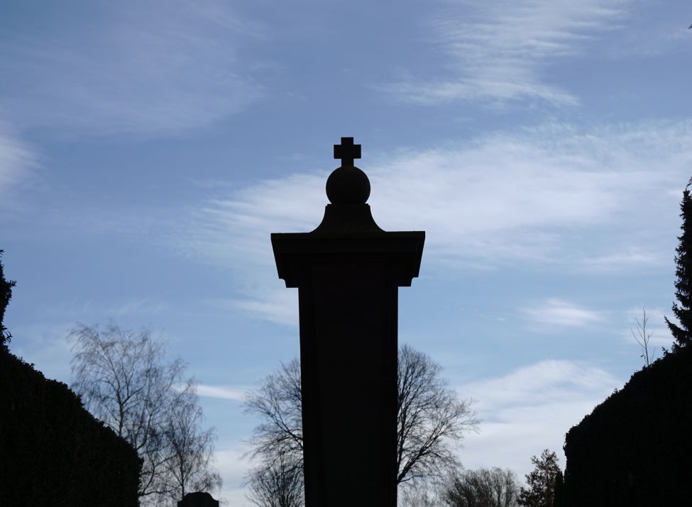 Die Spitze des Gefallenendenkmals mit Kreuz und blauem Himmel