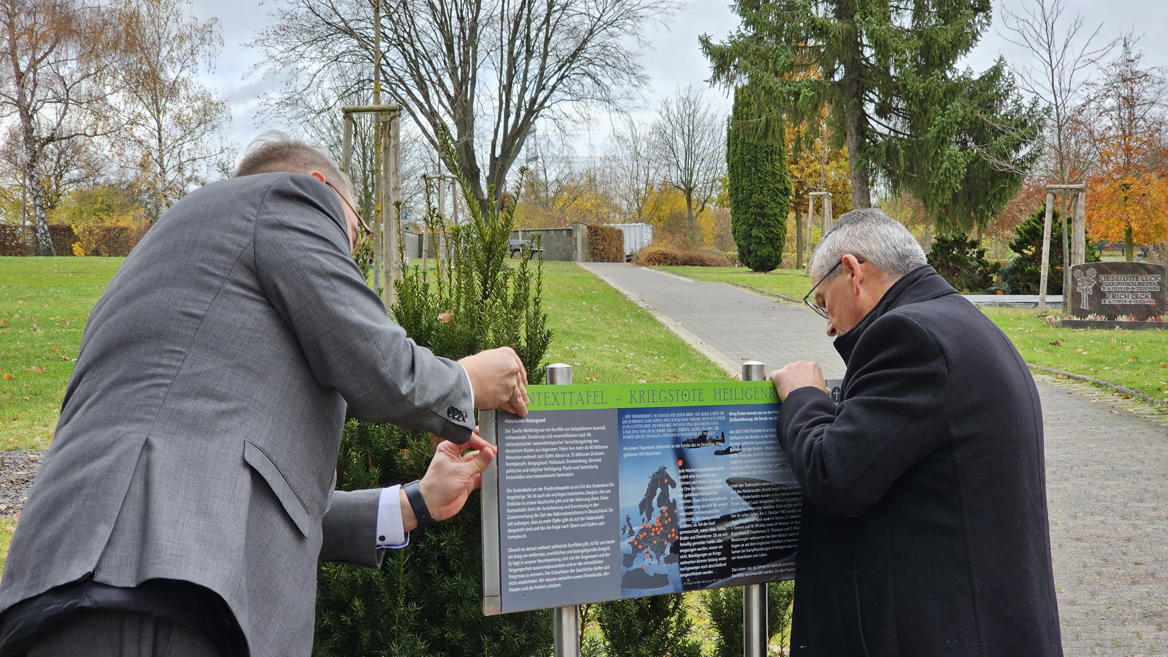 Bürgermeister Brückmann und Landrat Siebert legen zusammen mit den Schülerinnen und Schülern selbst Hand an und Schrauben die Tafel fest.